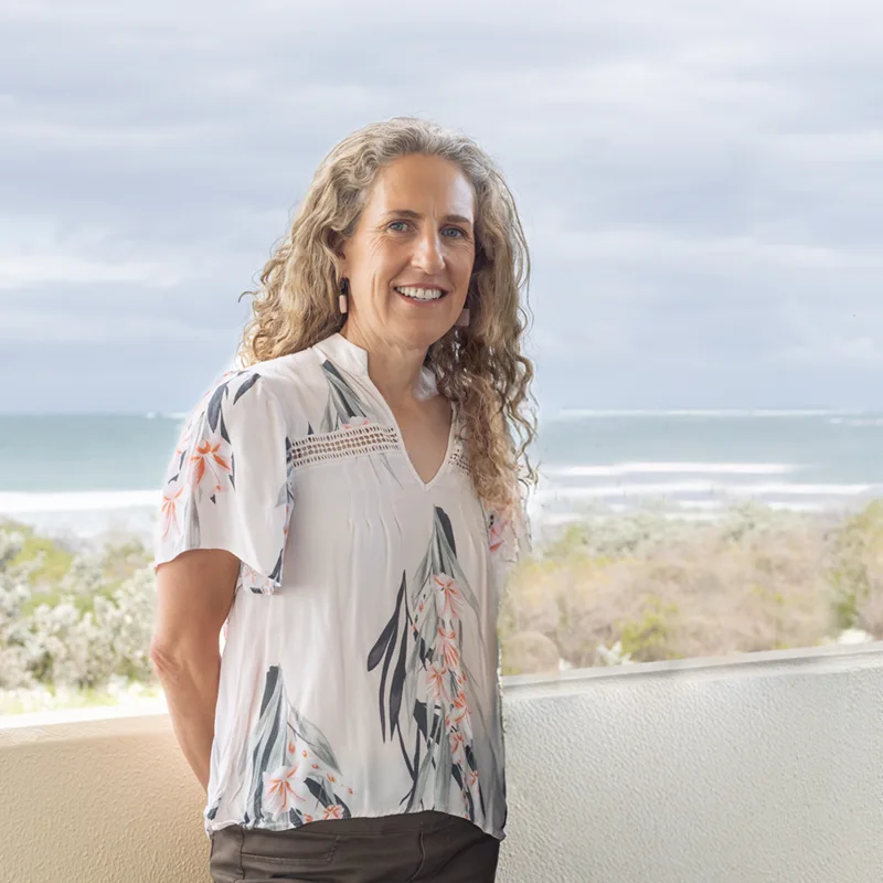 Woman standing in front of wall with beach background. Sally McKenzie, Pelvic Health Physio